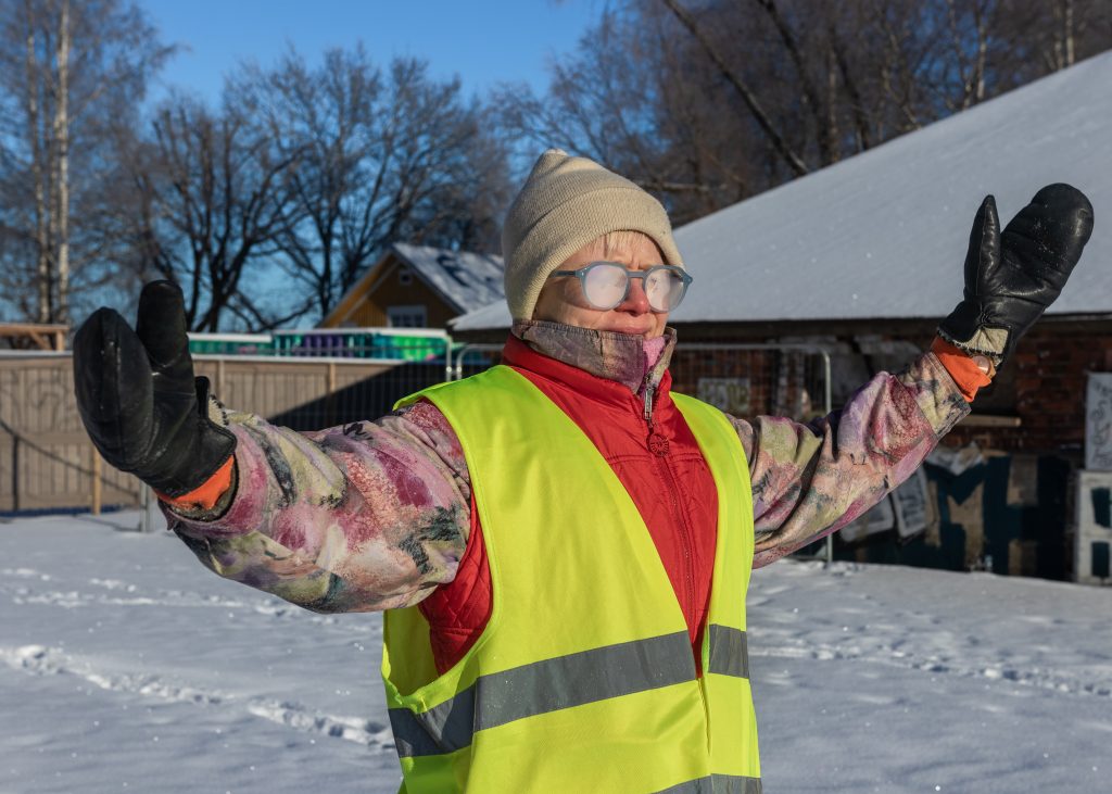 Hanna seisoo piha-aukiolla kädet kohotettuina silmälasit huurussa